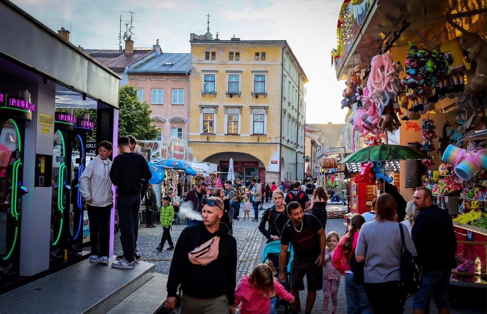 Dav návštěvníků na pouťové ulici za soumraku